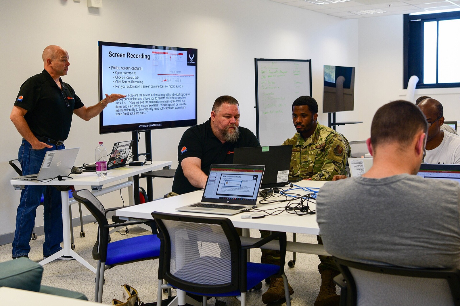 An instructor teaches a class of students working on laptops